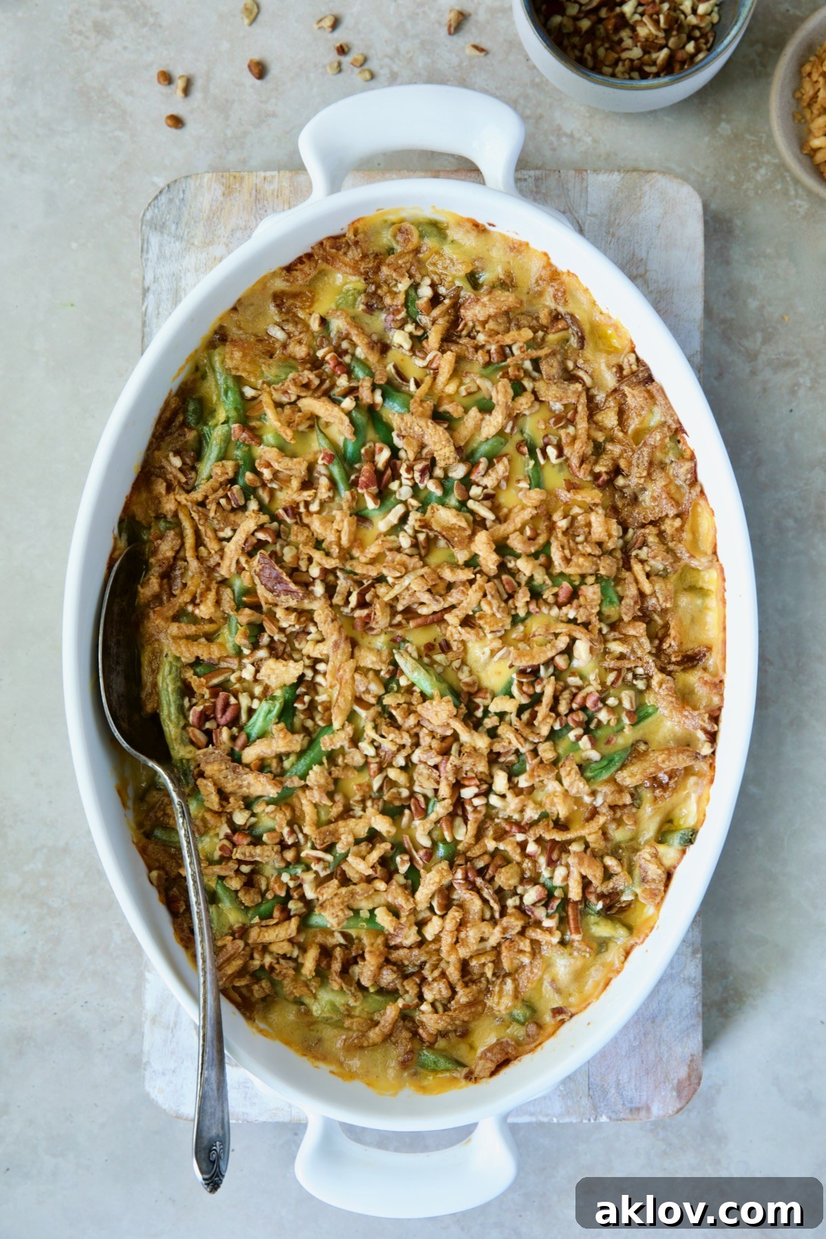 Irresistible Cheesy Green Bean Bake 13 Baked Cheesy Green Bean Casserole presented on a wooden cutting board with a serving spoon, golden and bubbling.