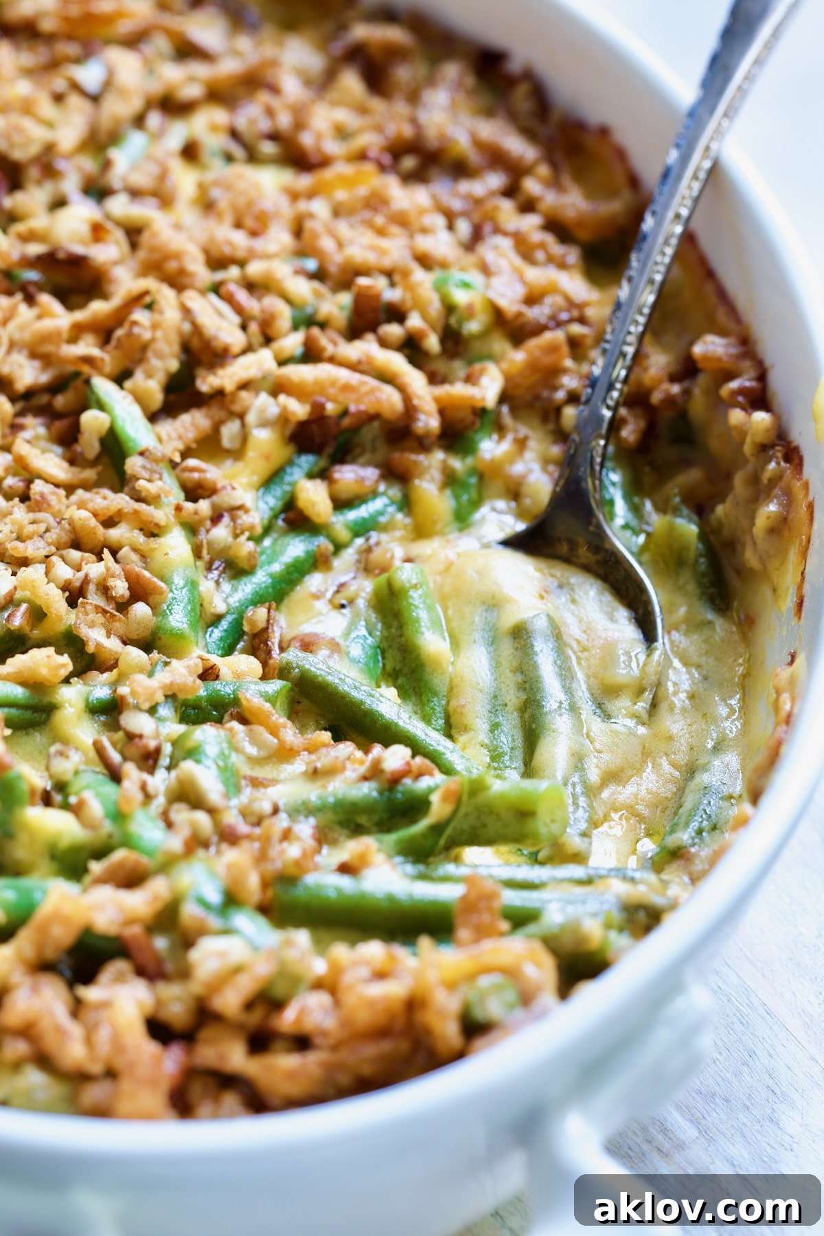 Irresistible Cheesy Green Bean Bake 3 Cheesy Green Bean Casserole in a white oval gratin dish with a portion spooned out, revealing the creamy sauce and tender green beans.