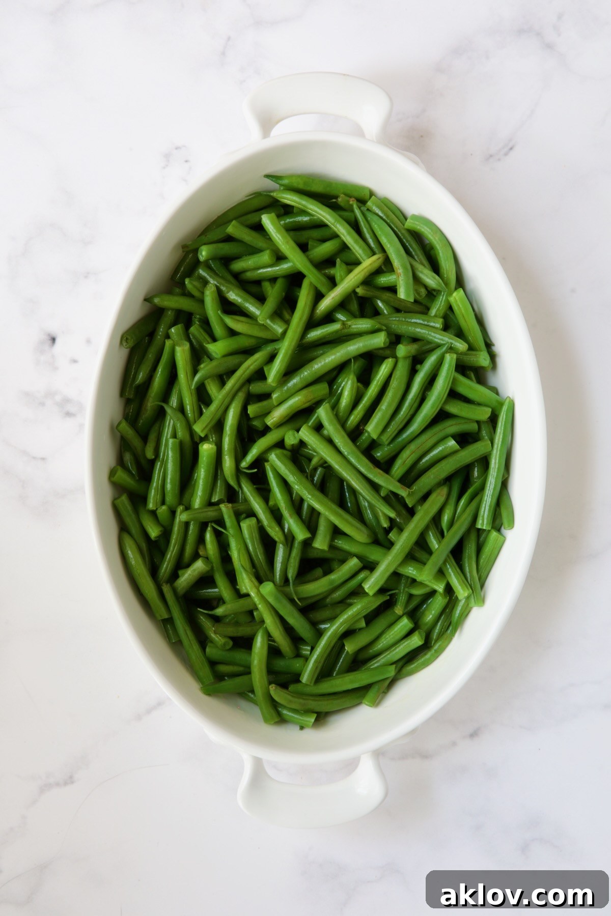 Irresistible Cheesy Green Bean Bake 6 Blanched green beans neatly arranged in a white oval gratin dish, ready for the sauce.