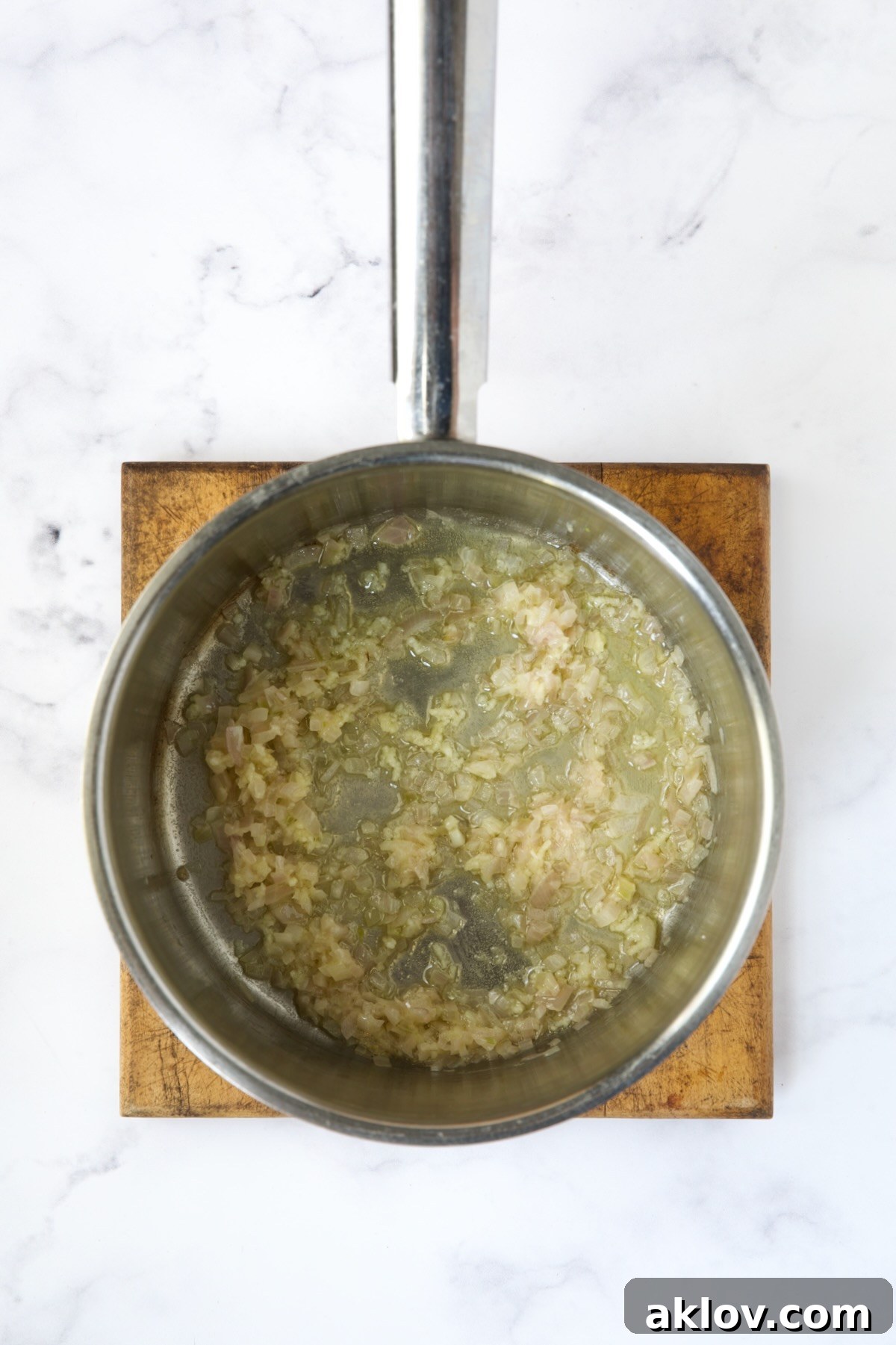 Irresistible Cheesy Green Bean Bake 7 Finely chopped shallots and minced garlic sautéing in melted butter in a stainless steel saucepan.