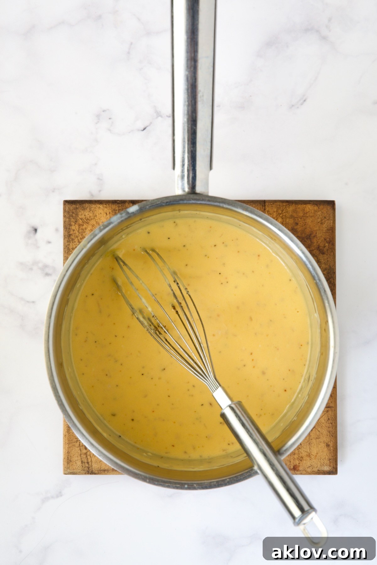 Irresistible Cheesy Green Bean Bake 10 Rich and smooth cheese sauce in a stainless steel saucepan, ready to be poured over green beans.