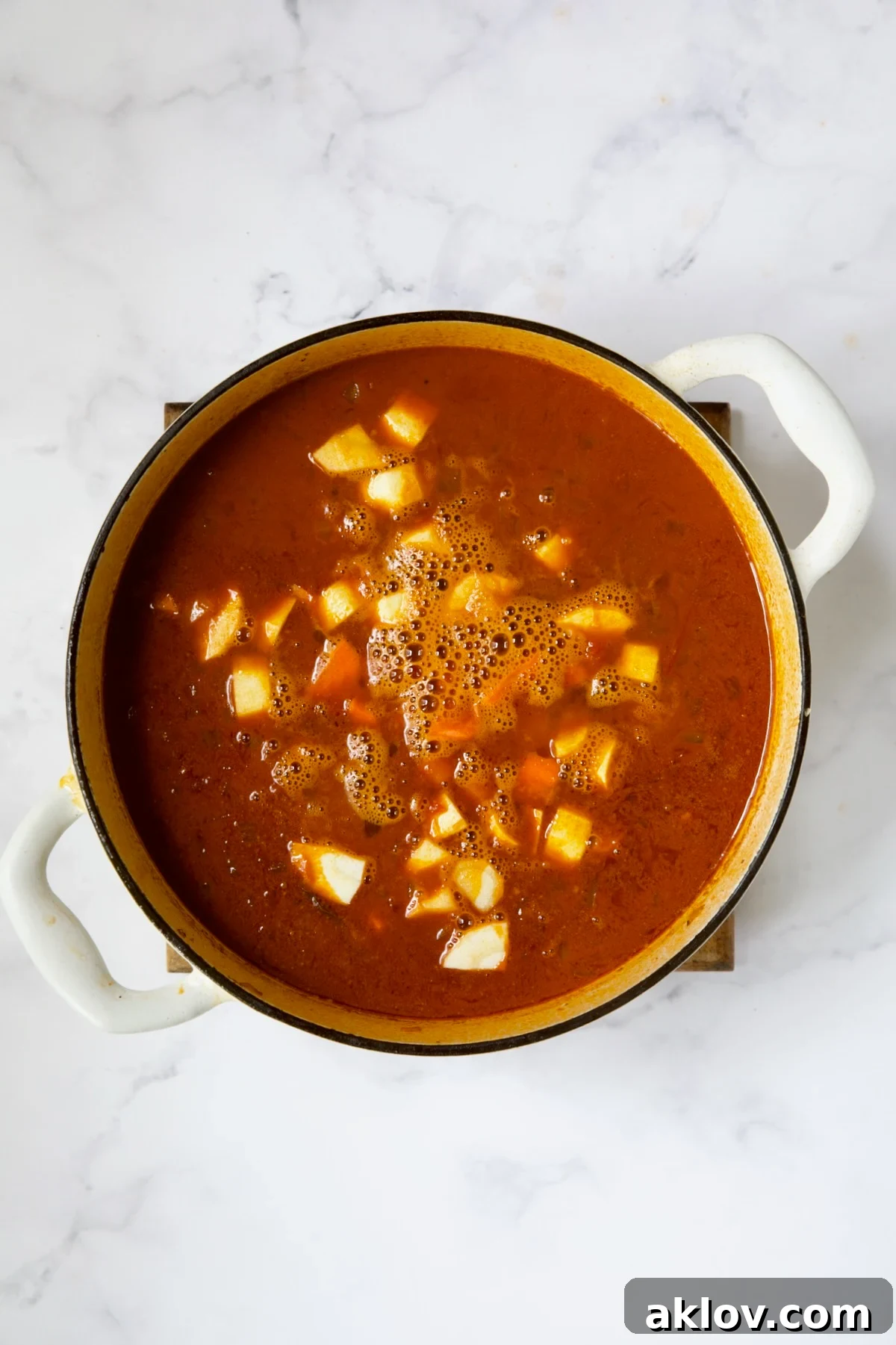 Carrots and parsnips added to goulash in white Dutch oven.
