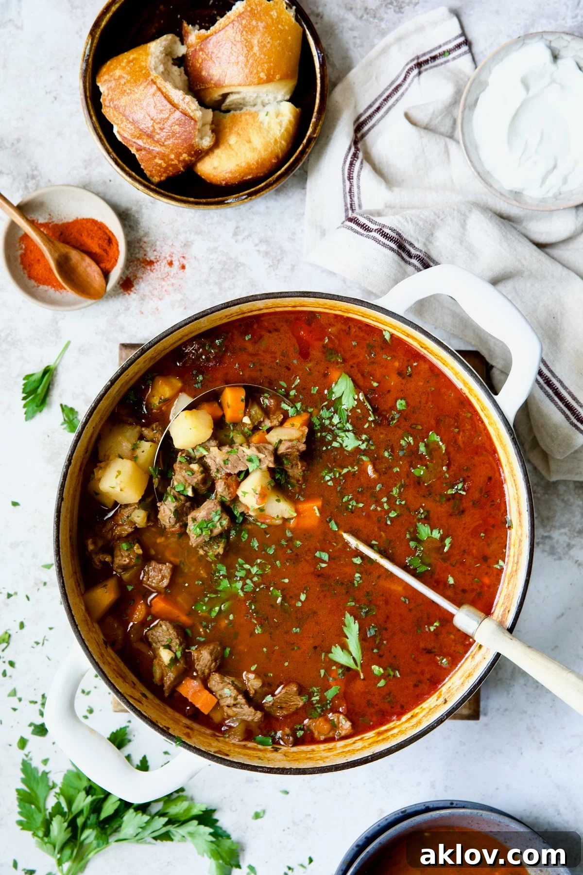 Traditional Hungarian Goulash Recipe in white Dutch oven garnished with fresh parsley.