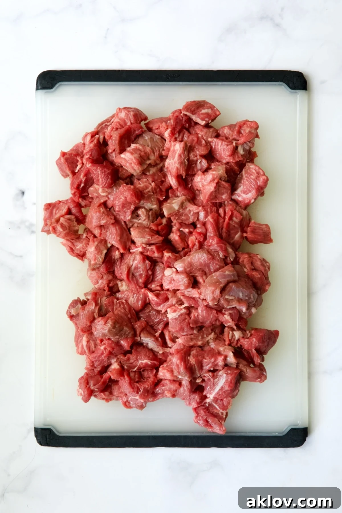 Pieces of beef on white plastic cutting board.