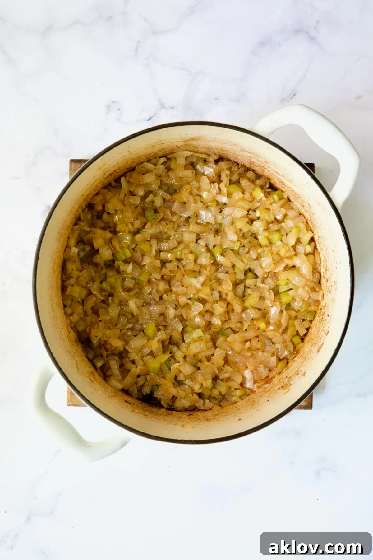 Cooked onions and celery in white Dutch oven.