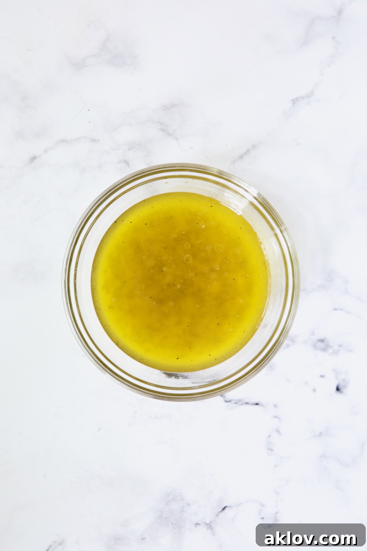 A vibrant lemon dressing, freshly whisked in a clear glass bowl, showcasing its readiness to elevate the salad with tangy flavor.