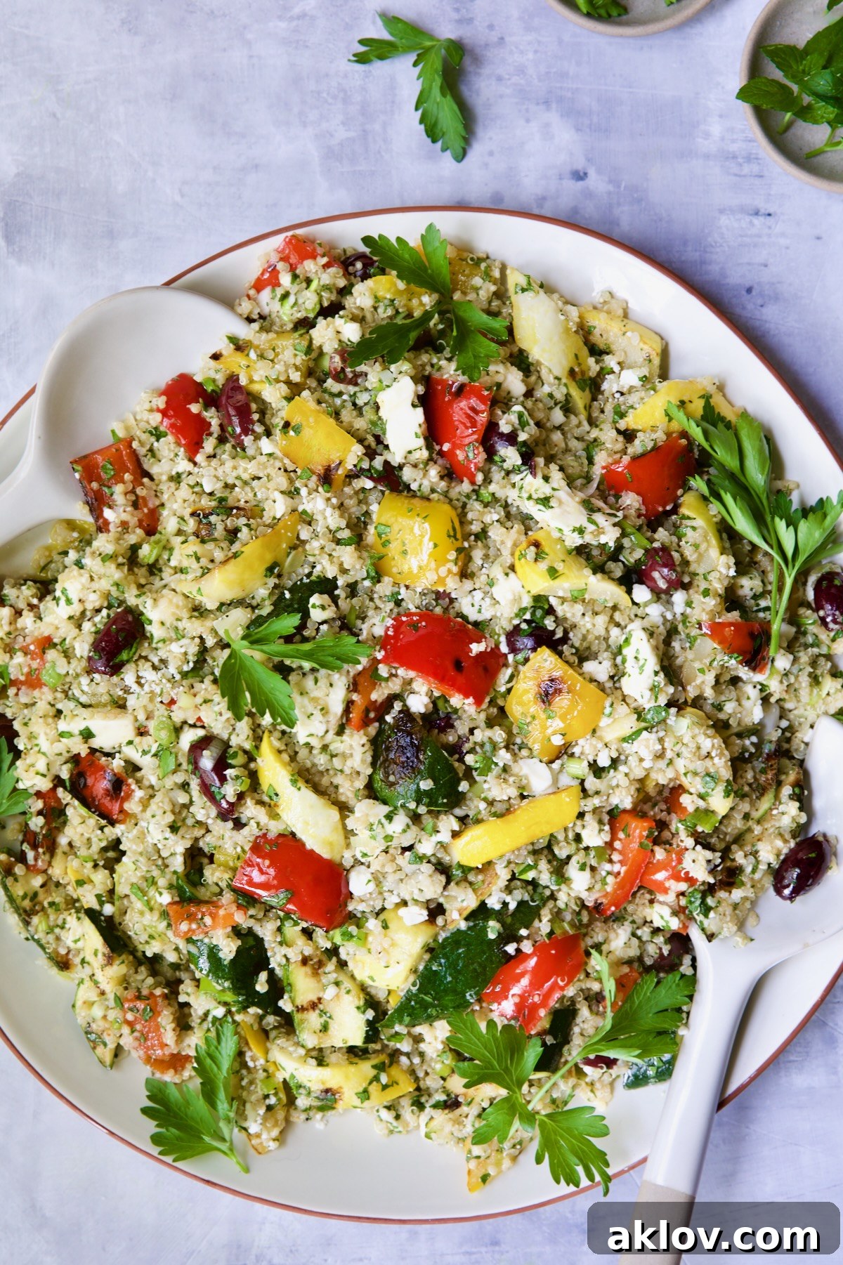 The spectacular Mediterranean Quinoa Salad with Grilled Vegetables, beautifully arranged on a round white platter and garnished with fresh parsley sprigs, ready to impress.