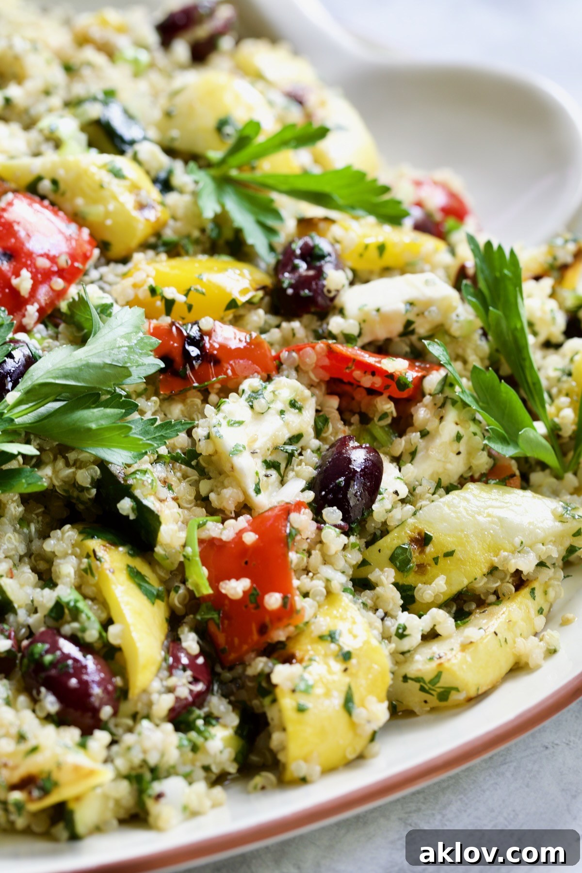 A close-up view of Mediterranean Quinoa Salad with Grilled Vegetables, served on a white platter with a serving spoon, highlighting its inviting texture and colors.