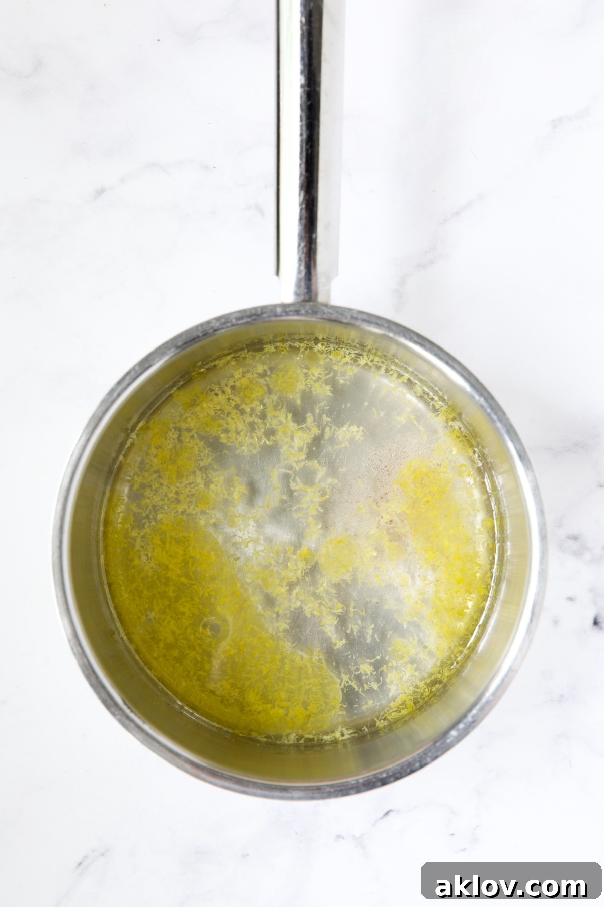 Water infused with lemon zest in a gleaming stainless steel saucepan, ready for quinoa, promising a flavorful base.