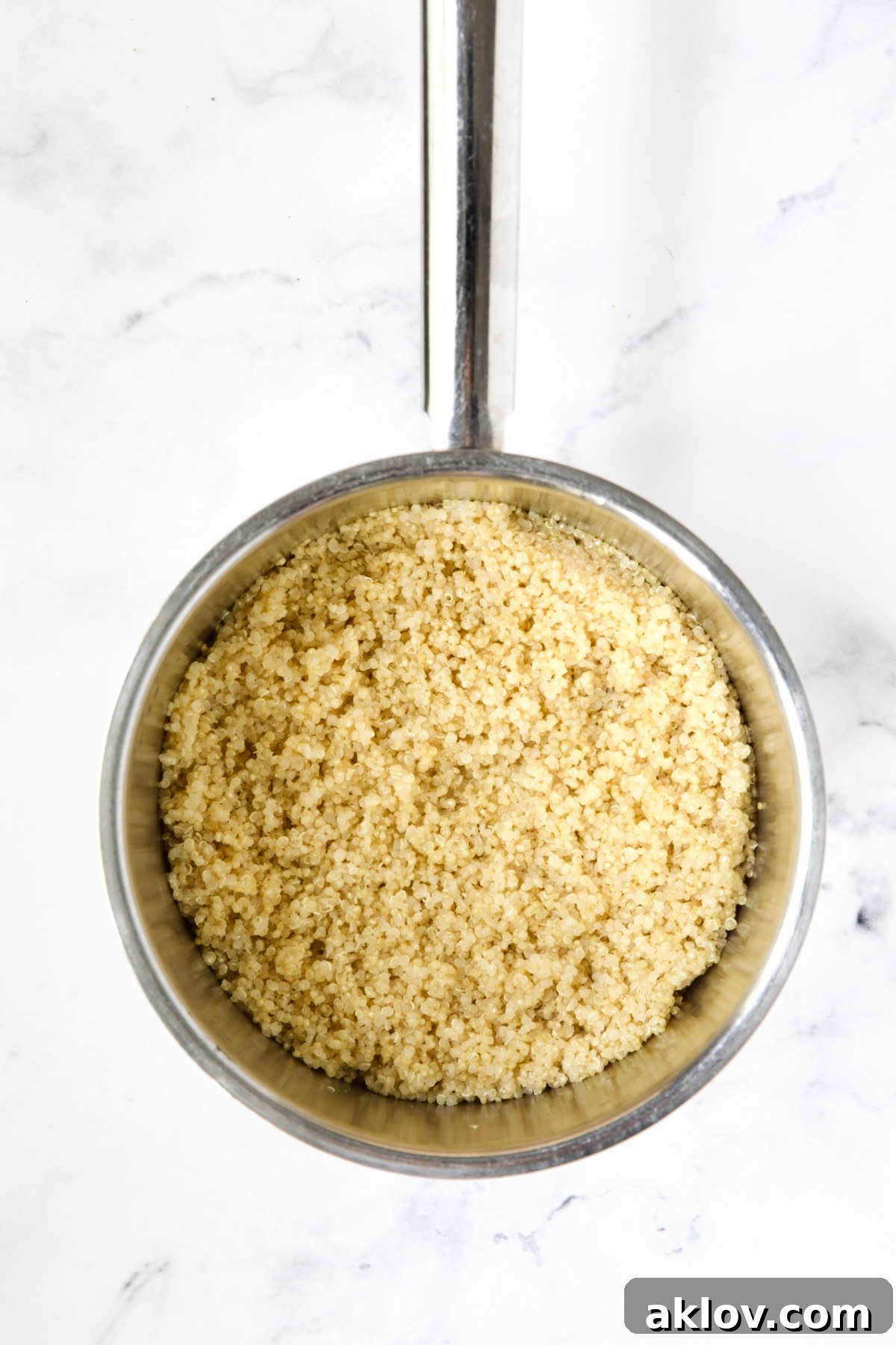 Perfectly cooked and fluffy quinoa, glistening in a stainless steel saucepan after resting, ready for the next steps.