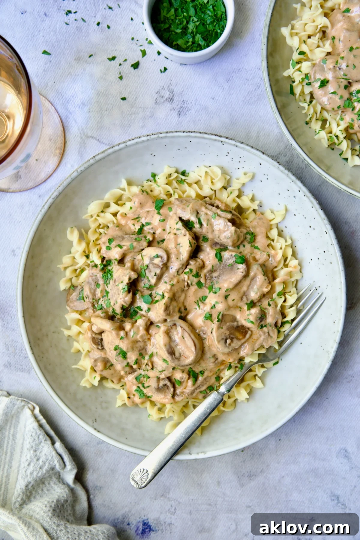 A beautifully plated serving of homemade Beef Stroganoff with tender beef strips, sautéed mushrooms, and a rich, creamy sauce, garnished with fresh parsley, served in a shallow bowl alongside egg noodles.