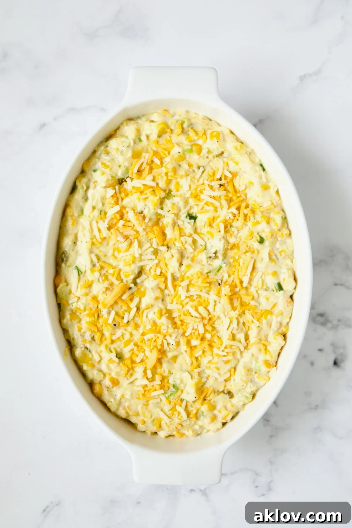 The unbaked casserole, topped with a generous layer of shredded cheese, ready for the oven.