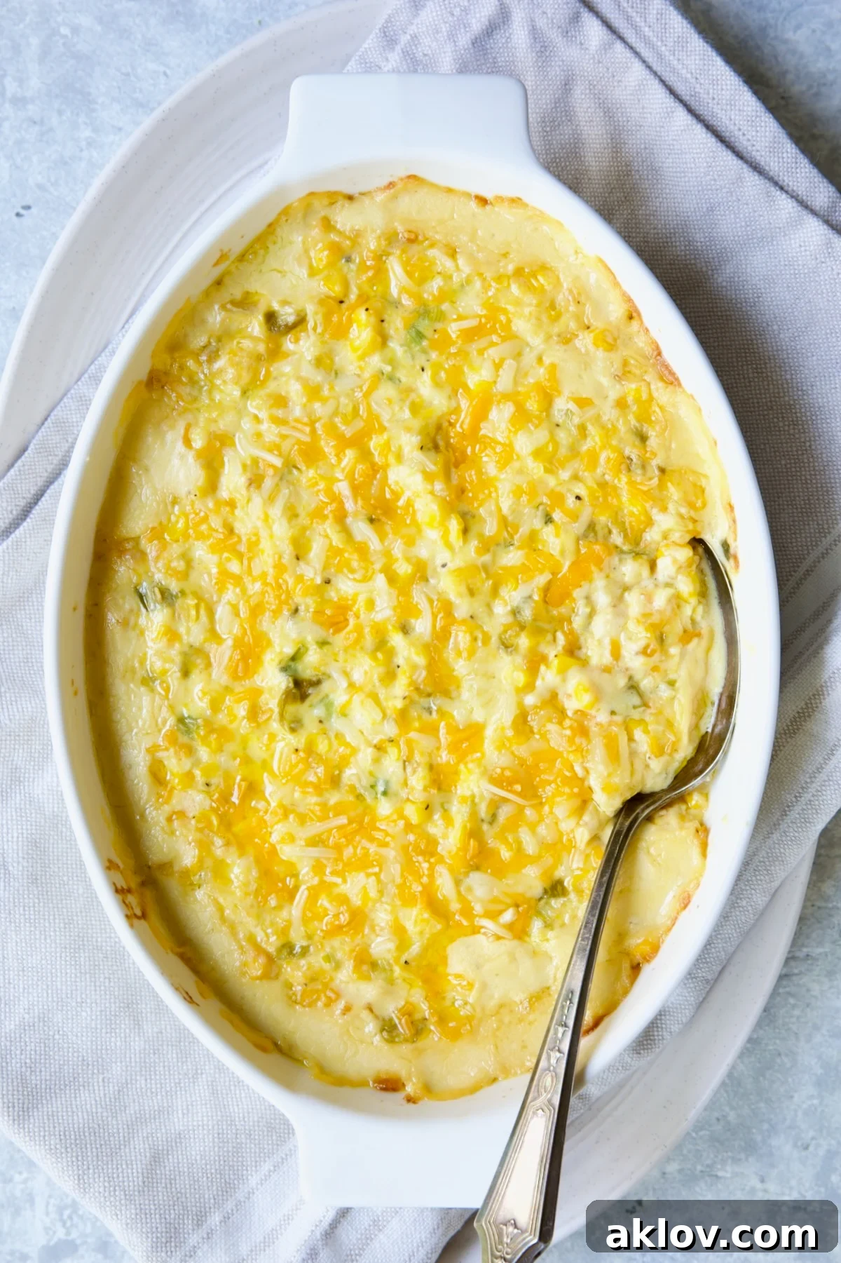 A glorious Cream Cheese Corn Casserole with Green Chiles, freshly baked and golden, in a white oval baking dish.