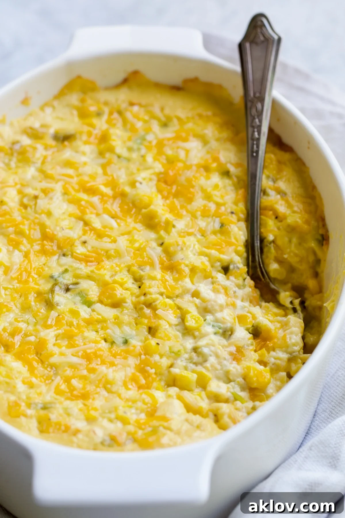 Cream Cheese Corn Casserole with Green Chiles, beautifully presented in a white oval baking dish with a portion scooped out, ready to be enjoyed.