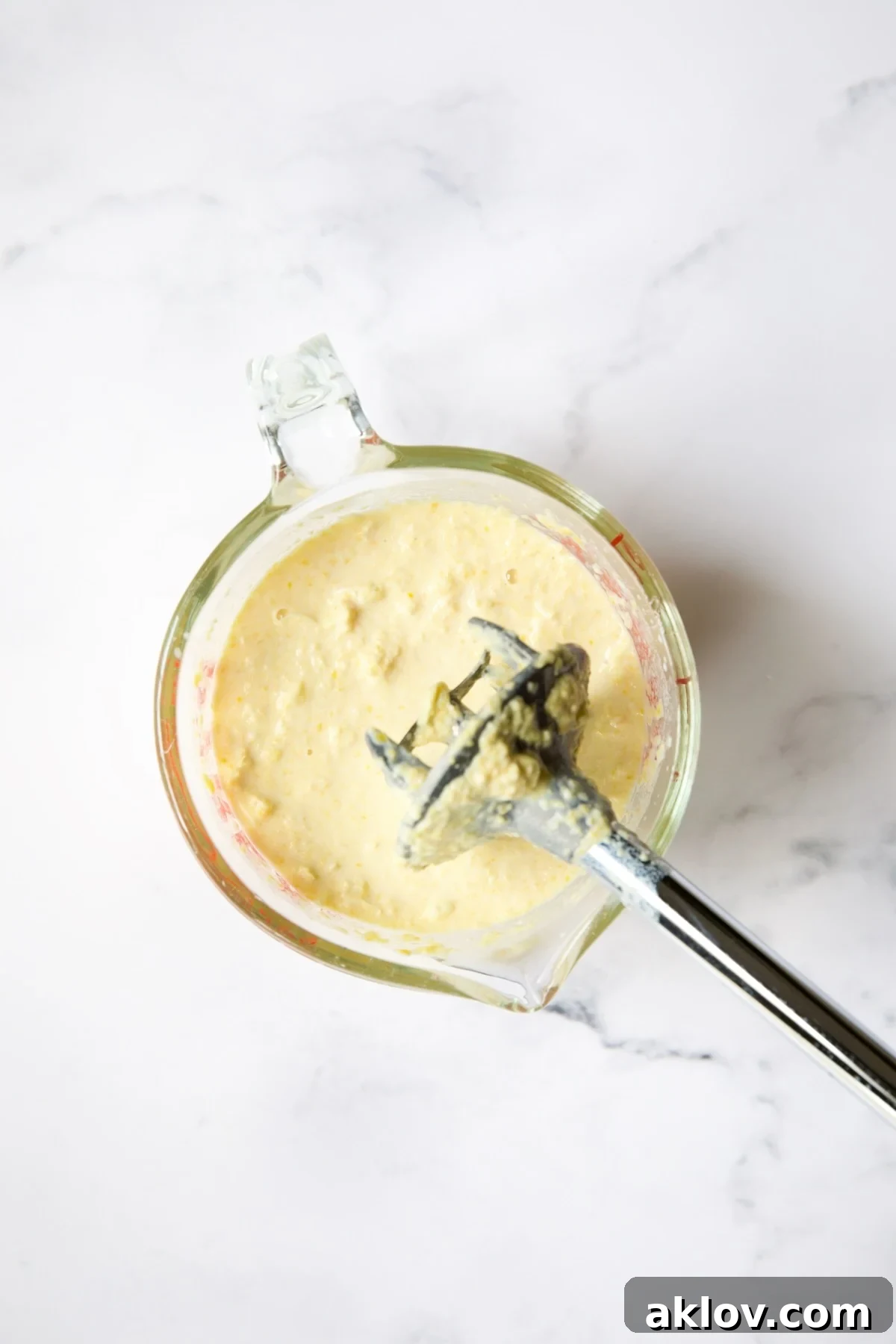 The pureed corn and milk mixture, now smooth and creamy, in a glass measuring cup.