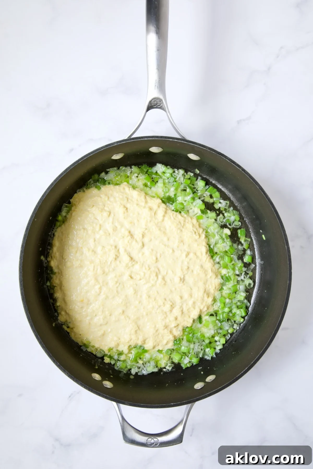Sautéed scallions and the pureed corn mixture simmering in a nonstick skillet.
