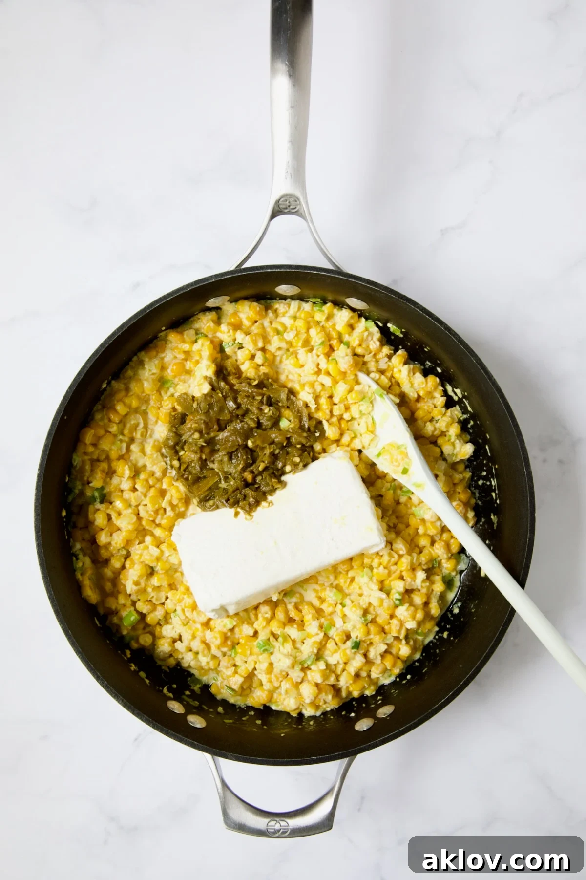 Corn mixture in a nonstick skillet with cream cheese and green chiles added, just before stirring to combine.