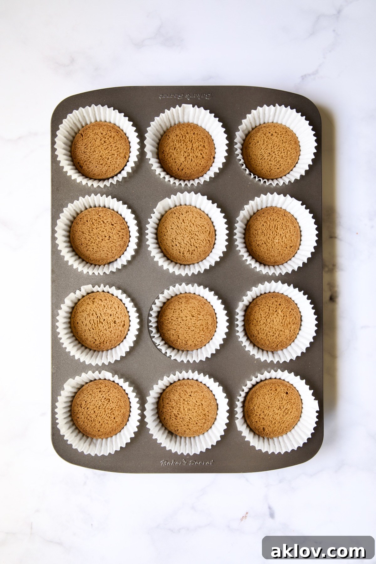 No-Bake Fall Pumpkin Cheesecake Bites 5 Muffin pan lined with white paper cups, each containing an upside-down gingersnap cookie.