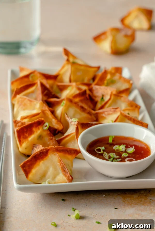 Air Fryer Crab Rangoon on white rectangular platter with dipping sauce.