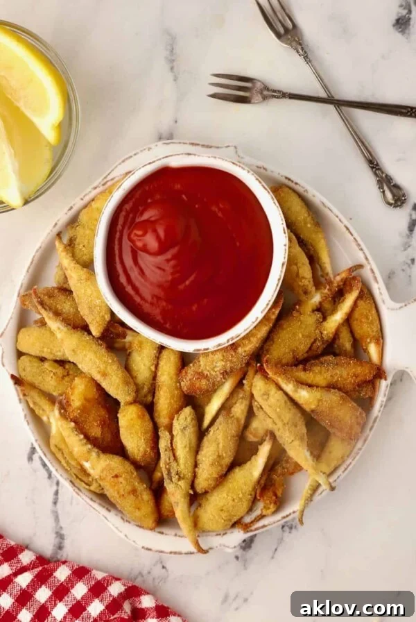 Fried Crab Claws with cocktail dipping sauce on white fish-shaped plate.