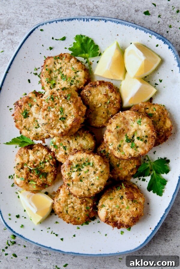 Maryland-Style Crab Cakes on blue-rimmed platter garnished with chopped fresh parsley, parsley sprigs and lemon wedges.