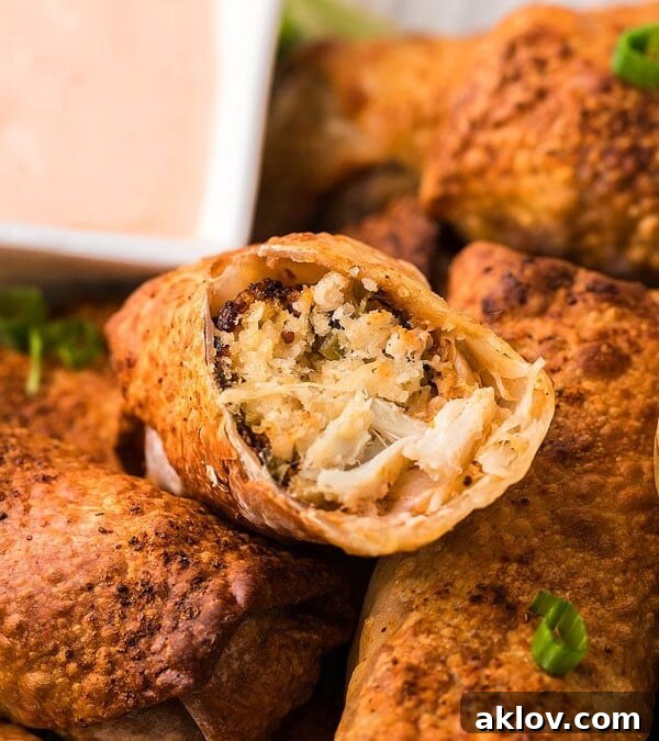 Air Fryer Crab Cake Egg Rolls cut to expose filling with dipping sauce in the background.