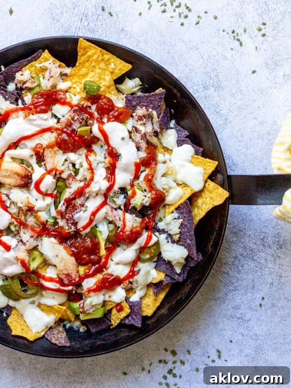 Crab Nachos in skillet with yellow striped towel on blue background.