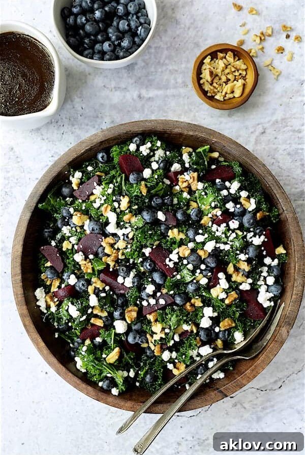 Massaged Kale, Beet and Blueberry Salad with Honey - Balsamic Dressing - Overhead hero shot of salad in wood bowl on gray stone background