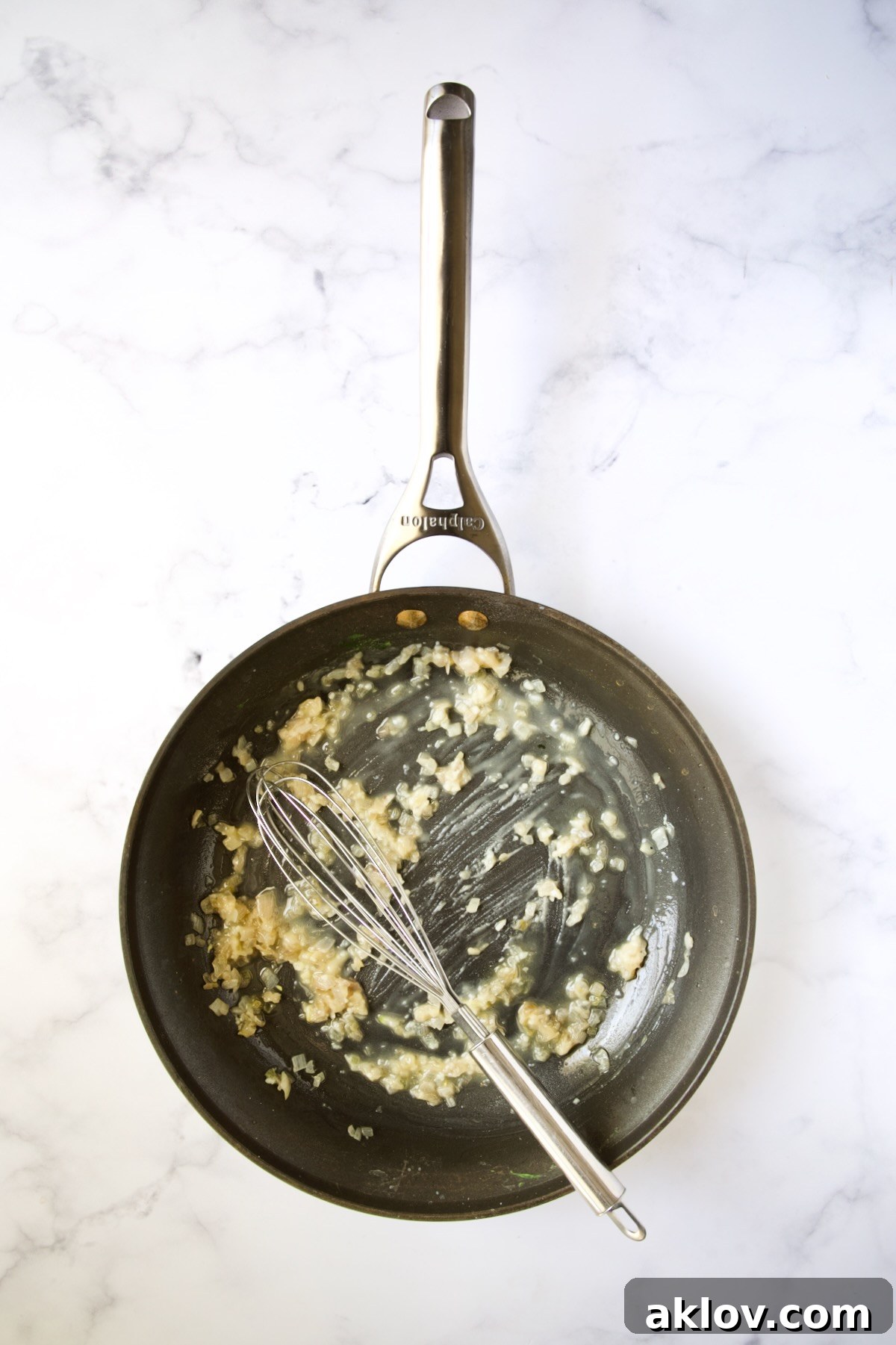 Flour being whisked into cooked shallots and butter in a nonstick skillet.