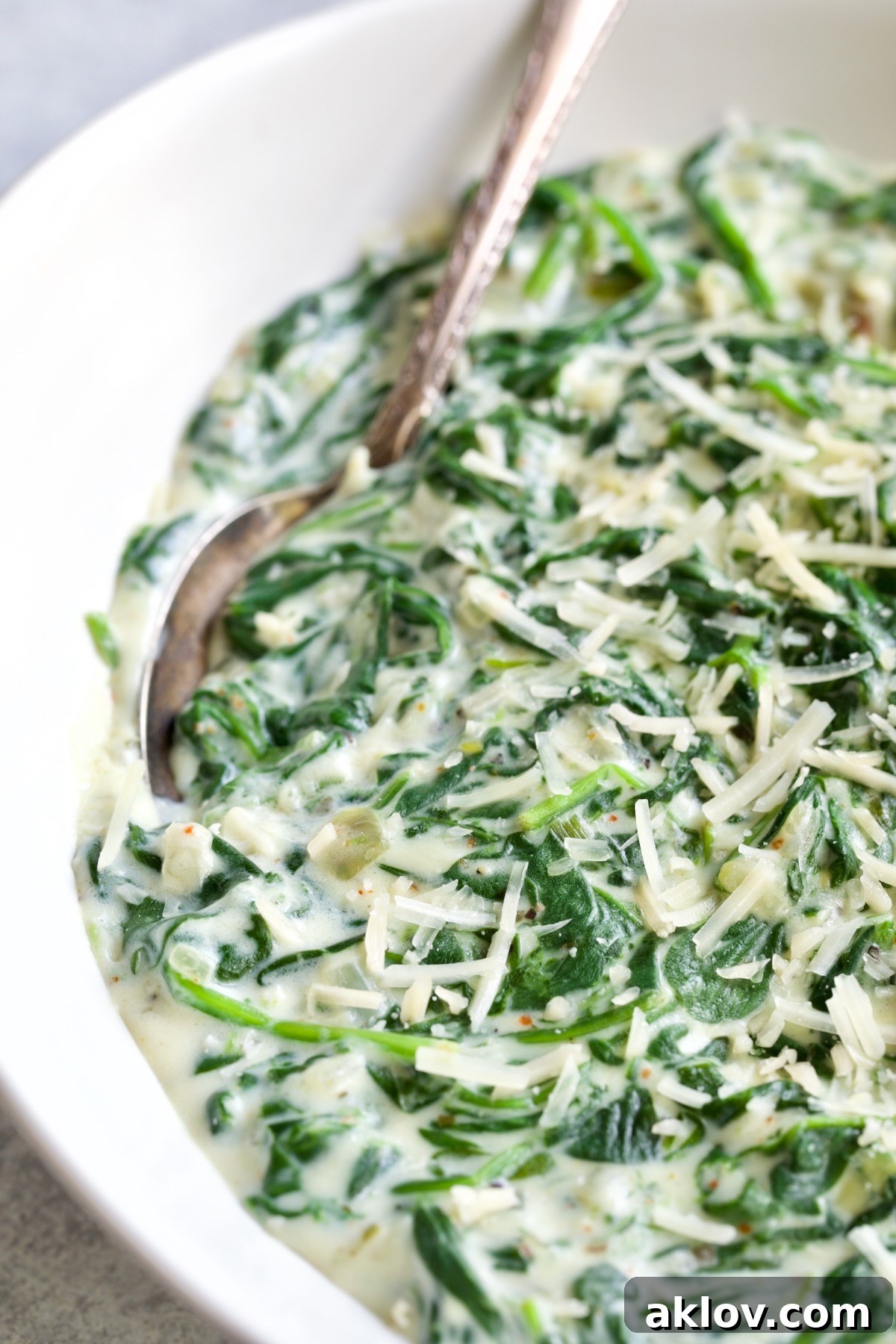 Steakhouse Creamed Spinach in a white oval bowl with a serving spoon.
