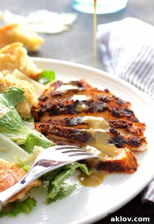 A vibrant Blackened Chicken Caesar Salad with golden sourdough croutons, elegantly drizzled with dressing over perfectly seasoned chicken.