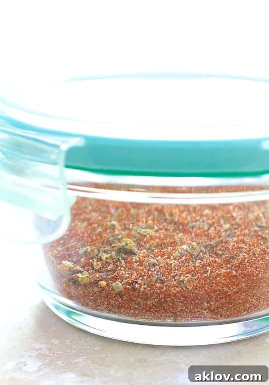 Close-up photo of a vibrant, custom blackening spice mix in a clear glass container, ready for use.