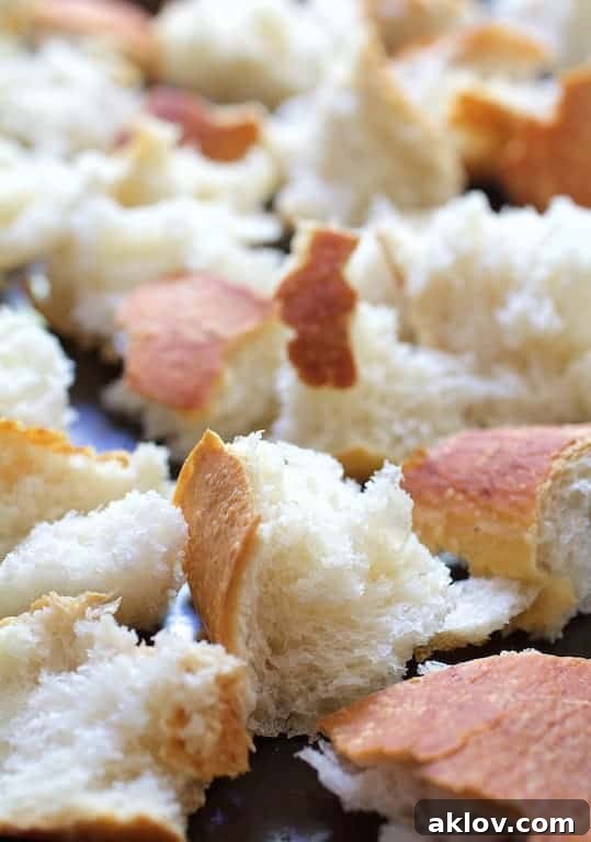 Unbaked sourdough baguette pieces, seasoned and ready for the oven, destined to become crispy croutons.