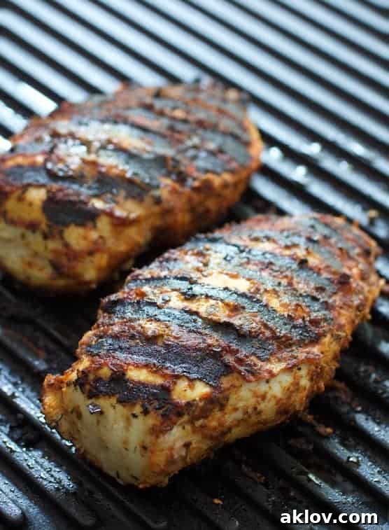 Grilled blackened chicken breasts on a grill pan, showing the rich, dark crust of perfectly cooked chicken.