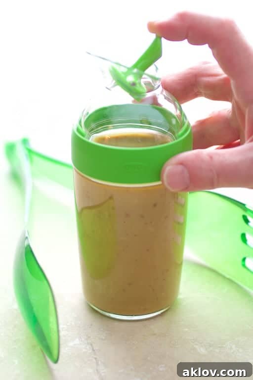 Rich, creamy Caesar dressing in a glass container, ready to be poured over a fresh salad.