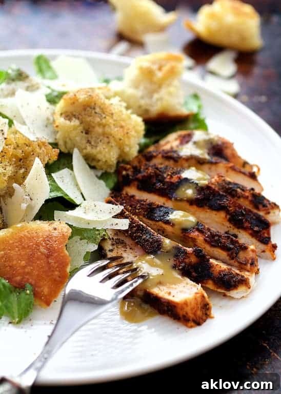 Sliced Blackened Chicken Caesar Salad on a white plate with a fork digging into one of the slices, highlighting the delicious textures.