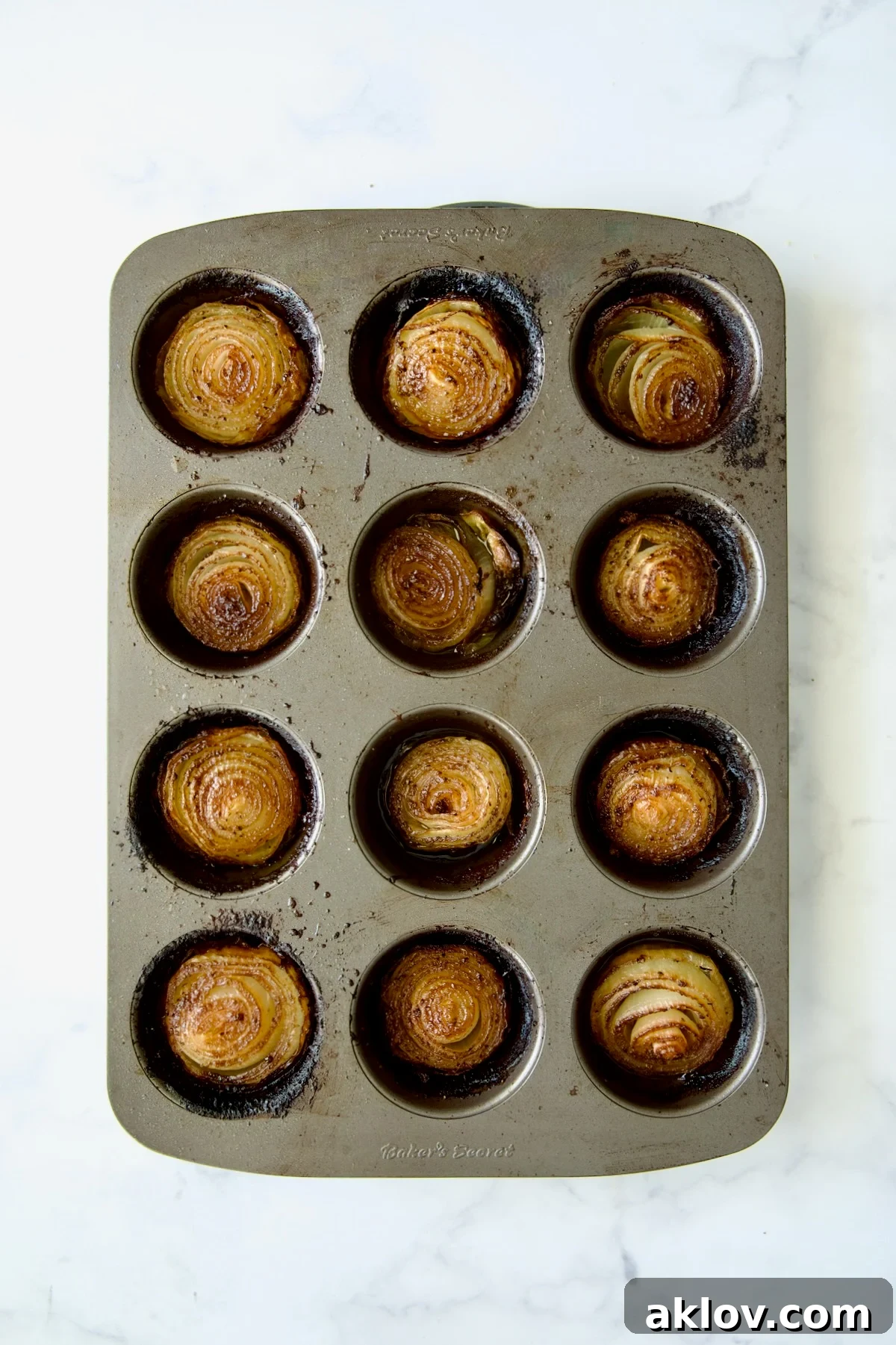 Fully roasted onions in a nonstick muffin pan after one hour of baking, showcasing their deep caramelization and perfect tenderness.