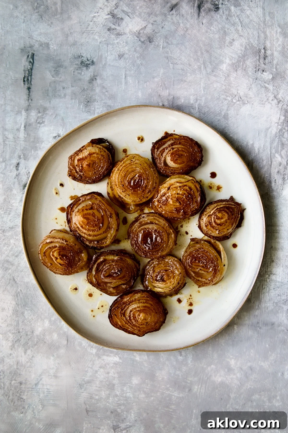 A serving of beautifully roasted onions on an elegant round plate, ready to be enjoyed as a gourmet side dish.