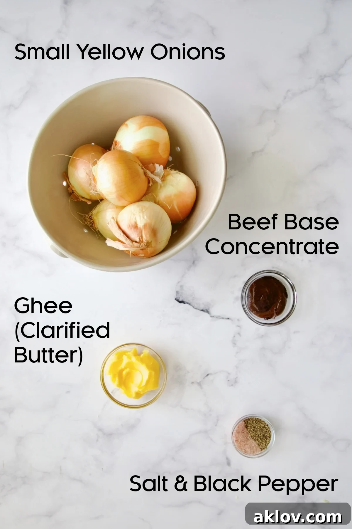 A selection of fresh ingredients for roasted onions, including small yellow onions, ghee, and beef base concentrate, arranged in elegant glass bowls.
