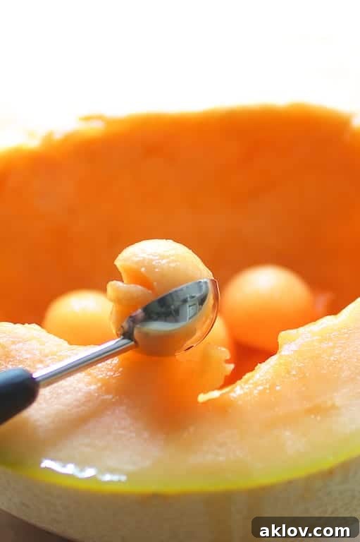 Detailed photo showing the process of making uniform cantaloupe balls using a melon baller, highlighting precision and preparation.