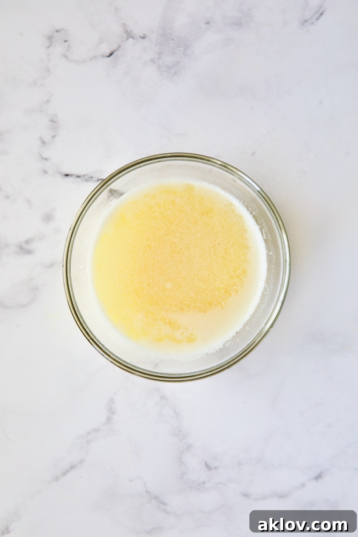 Smooth, melted butter in a glass bowl, infused with garlic, after microwaving.