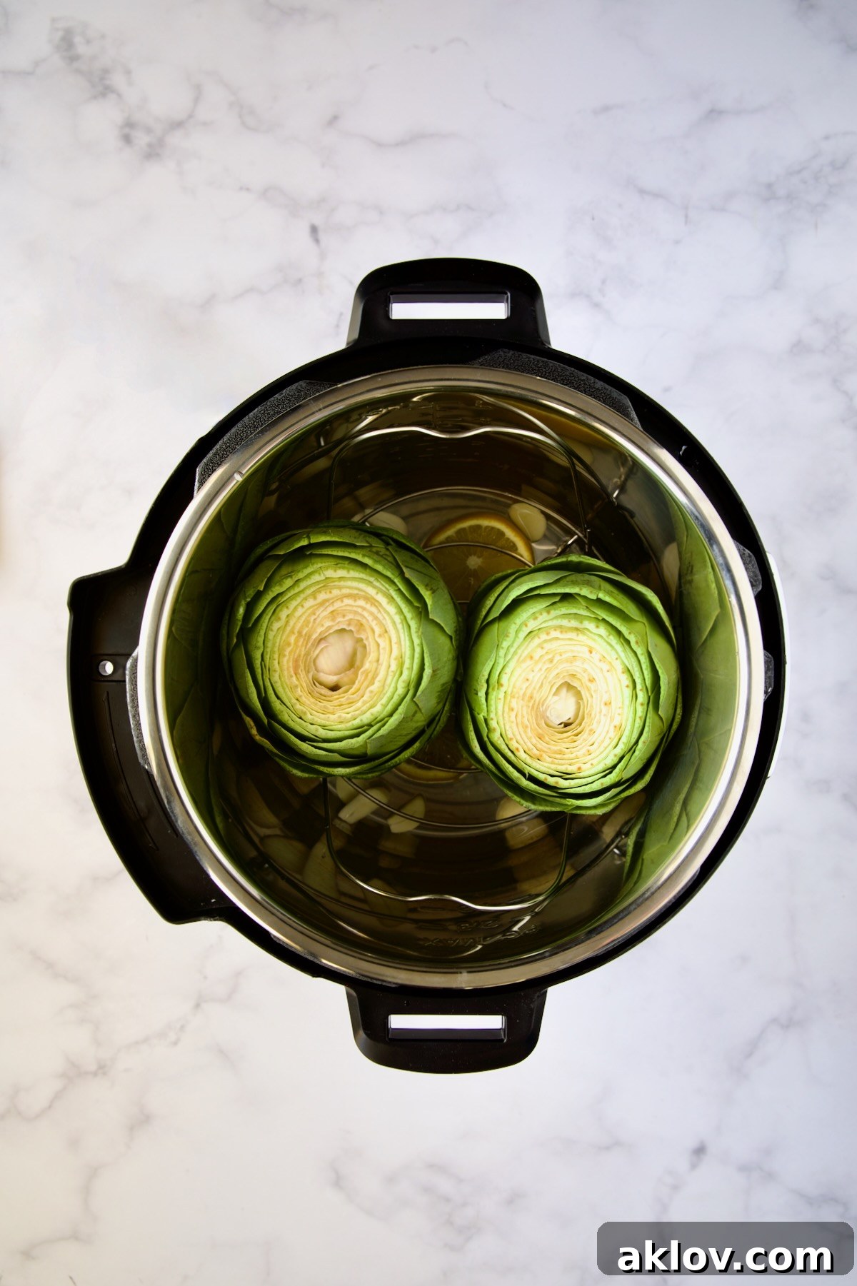 Uncooked, prepared artichokes neatly placed onto the steaming rack inside an Instant Pot, ready for pressure cooking.