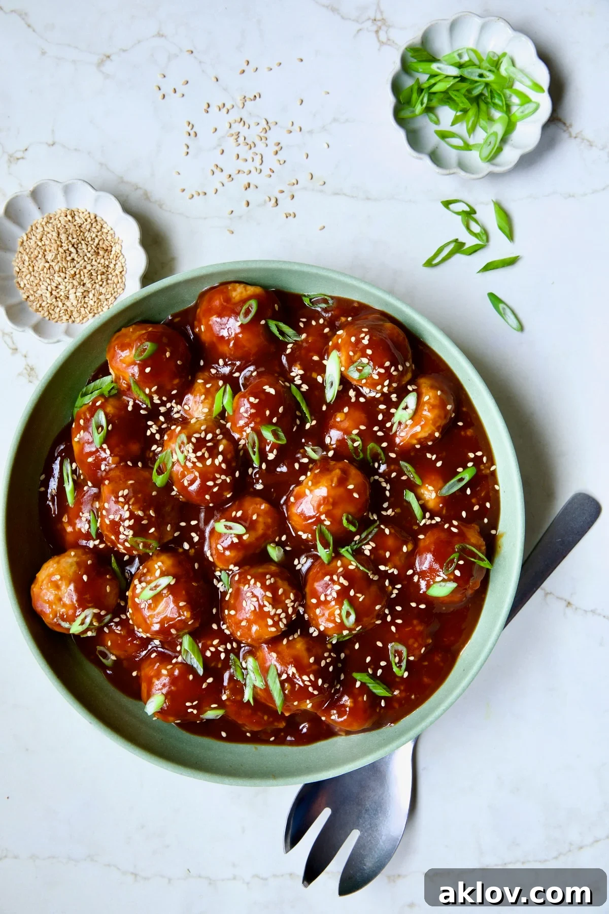 The final dish: Asian Chicken Meatballs in a vibrant green bowl, generously coated in sauce and garnished.