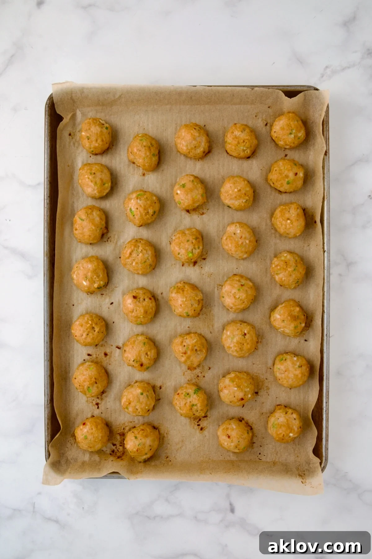 Perfectly cooked chicken meatballs on a parchment paper-lined baking sheet, golden and ready.