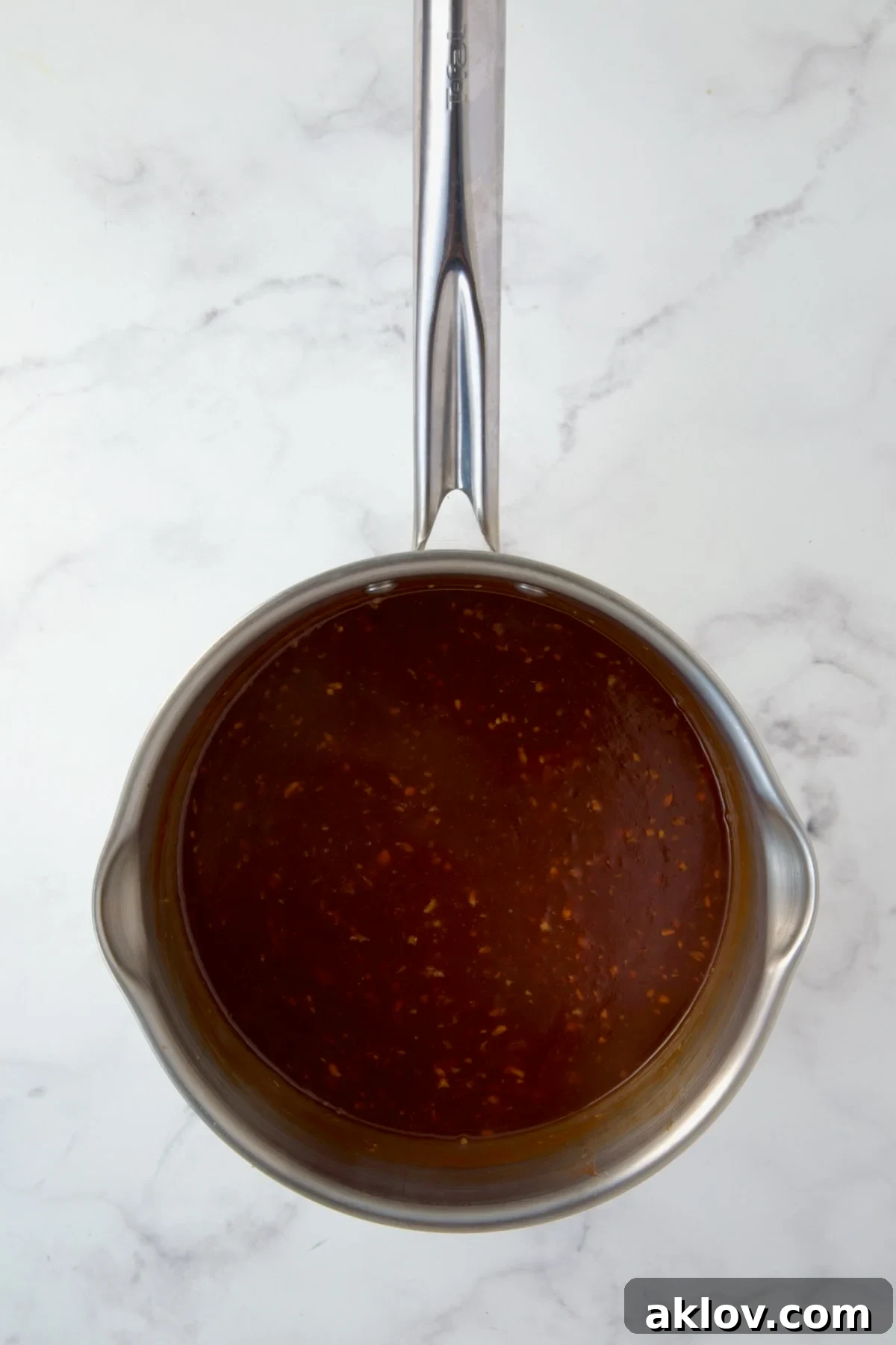 The savory Asian sauce simmering in a stainless steel saucepan.