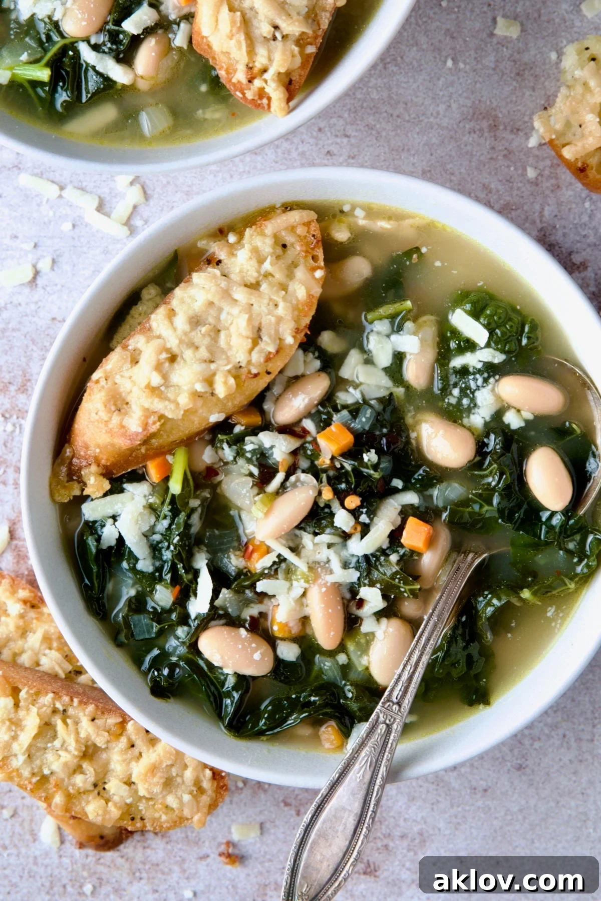 A solitary, elegant bowl of White Bean Kale Soup, perfectly presented with a golden Parmesan Toast, highlighting the comforting simplicity of the dish.