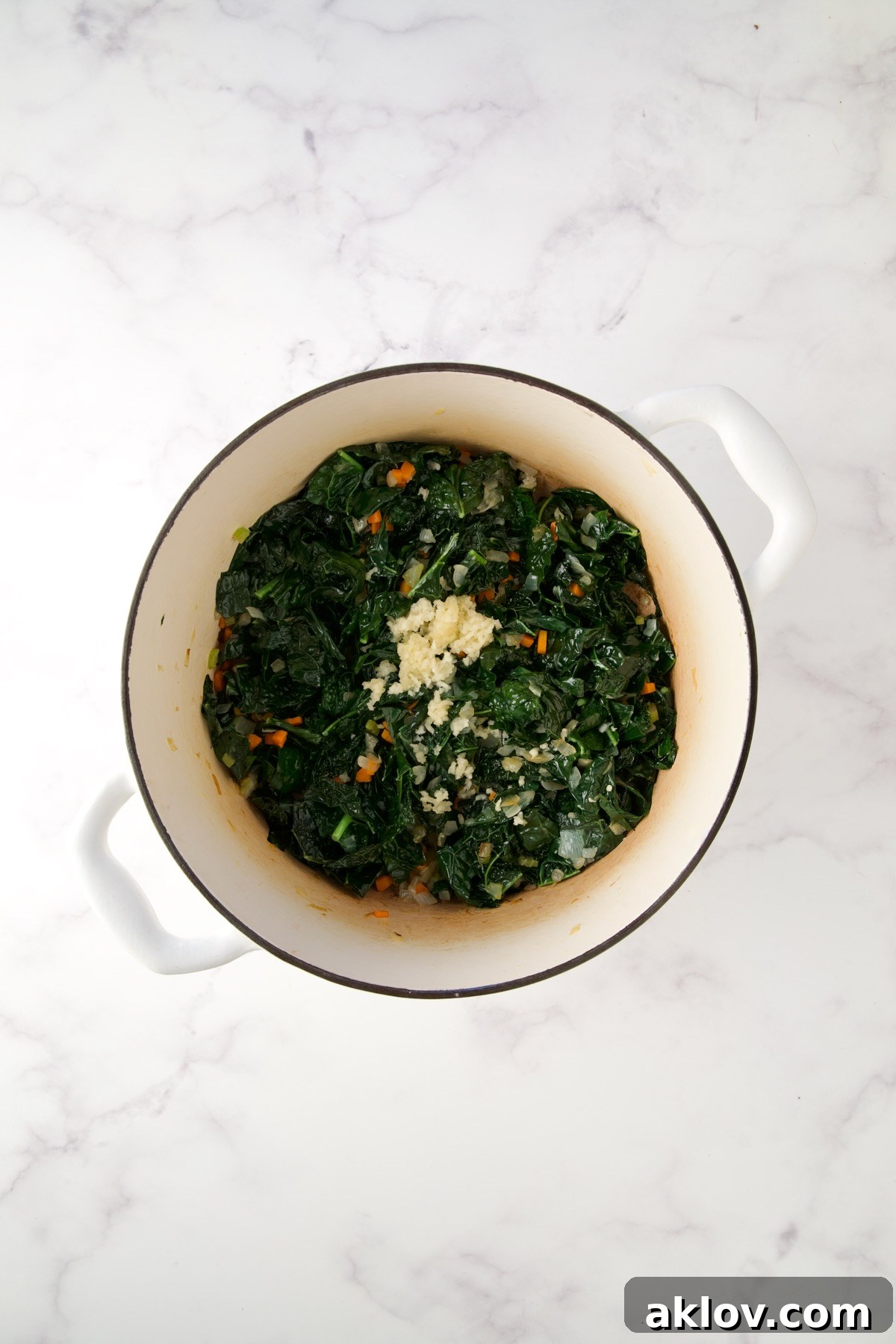 The softened mixture of onions, carrots, celery, wilted kale, and fragrant garlic in the Dutch oven.