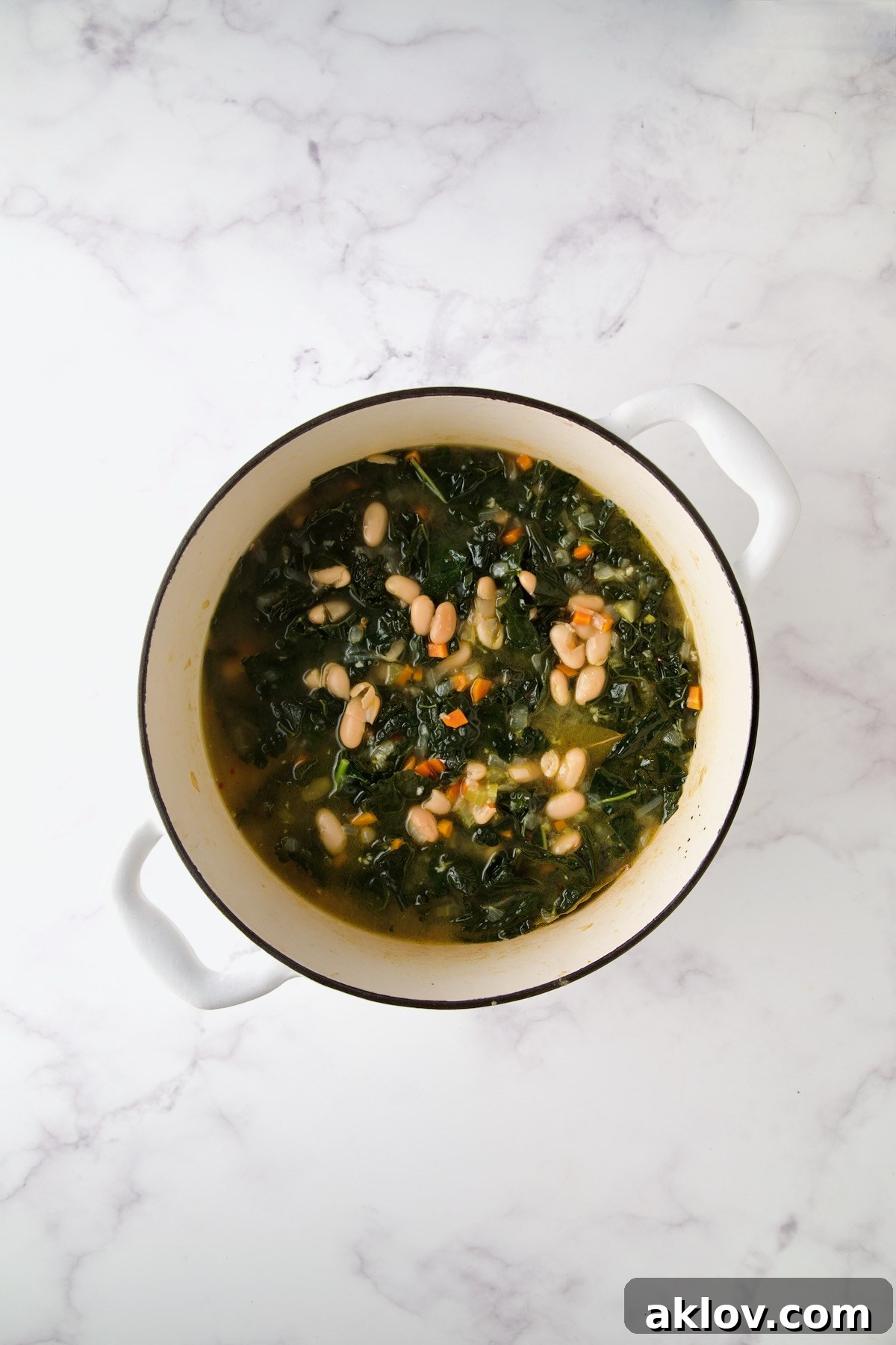 The finished White Bean Kale Soup, rich and comforting, ready to be served from the white Dutch oven.