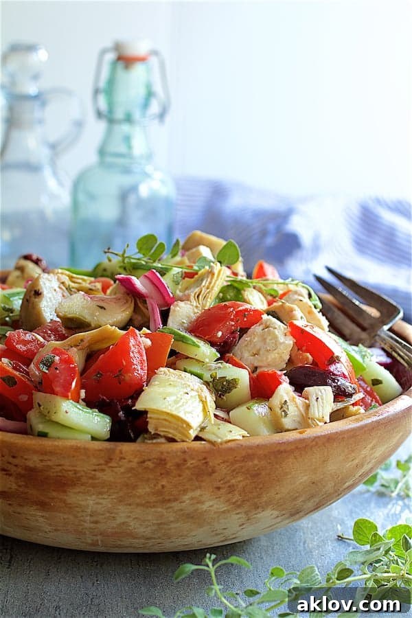 Photo of Greek Vegetable Salad with Marinated Feta Cheese in wood bowl garnished with fresh oregano with bottles in the background.