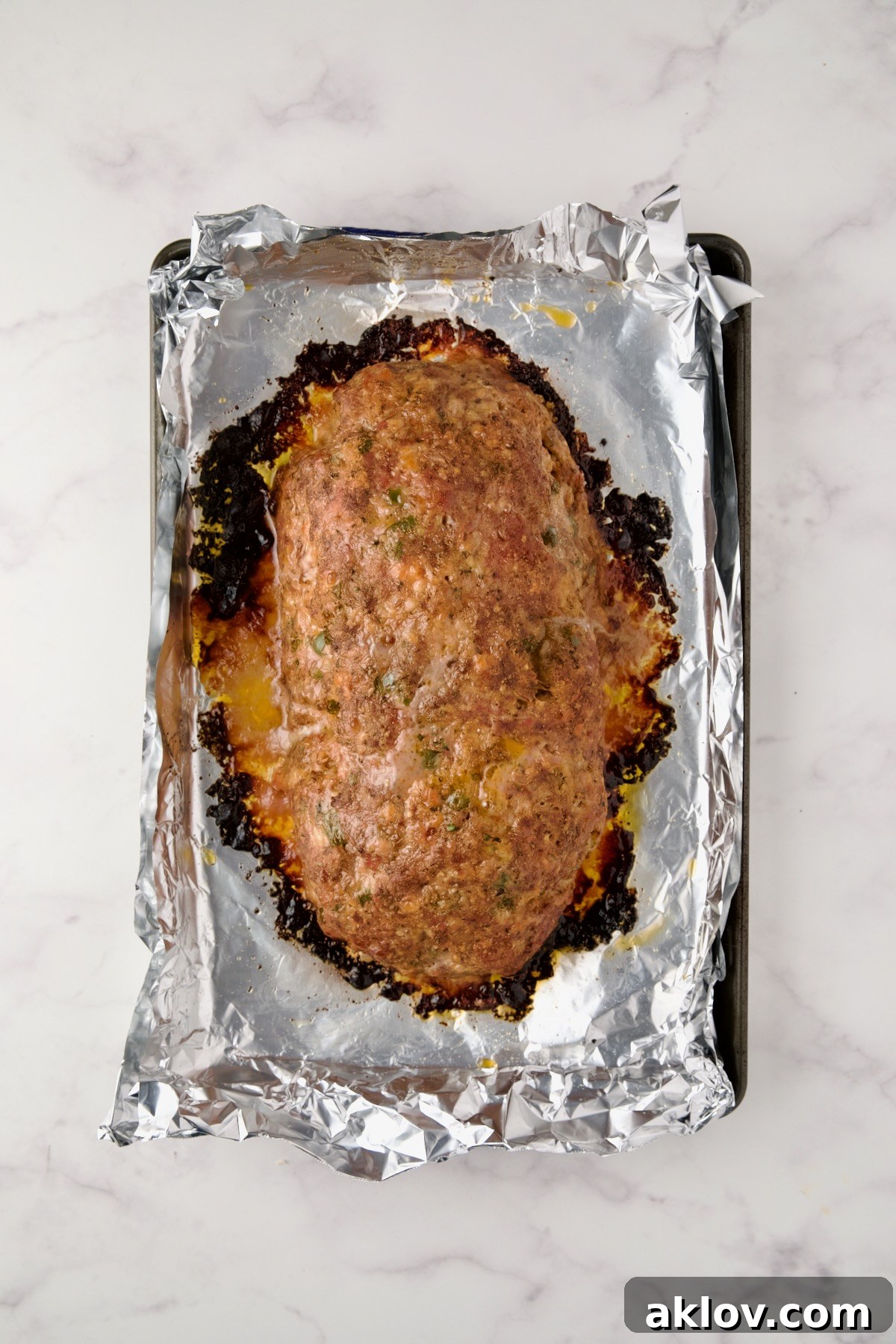 Baked meatloaf on an aluminum foil-lined rimmed baking sheet.